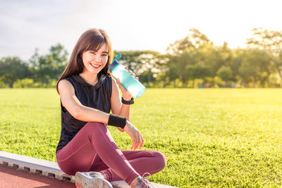 Portrait of smiling young woman sitting on field