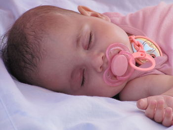 Close-up of cute baby girl sleeping on bed