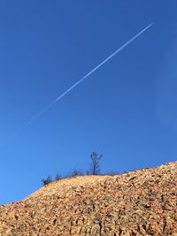 Low angle view of vapor trail against clear blue sky