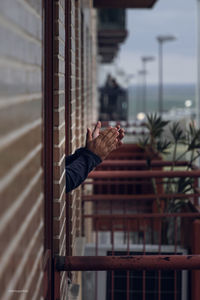 Cropped hand of man clapping out of window