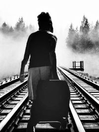 Rear view of a man standing on railroad track