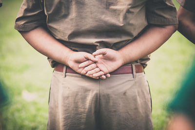 Midsection of woman holding umbrella standing on field