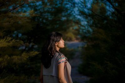 Young woman standing against trees