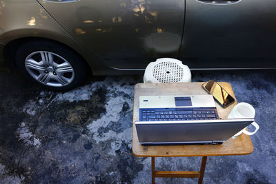 Photo of a laptop computer, smartphone, and coffee mug on a desk at a home garage