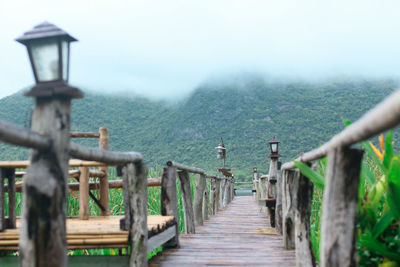 Footbridge by mountains against sky