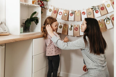 Mother with child opening christmas advent calendar tasks and gifts. toddler girl excited about