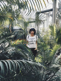 Portrait of woman standing by palm trees