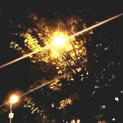 Low angle view of illuminated street lights at night