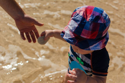 Cropped hand of mother with son at beach