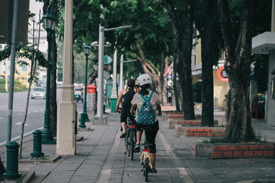 Rear view of women walking on footpath in city