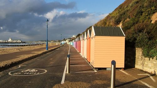 Road by seafront against sky