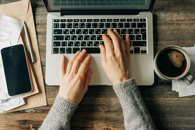 Top view of female hands typing on a laptop keyboard.