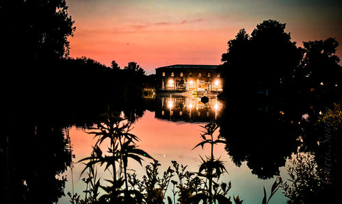 Silhouette trees by lake against sky during sunset