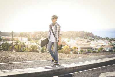 Teenager walking roadsude with skateboard. youth freedom concept