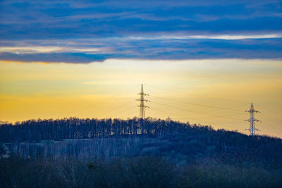 Electricity pylon on field against sky during sunset