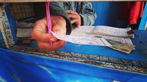 Cropped image of man giving bus ticket through window