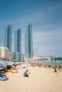 People at beach against sky in city