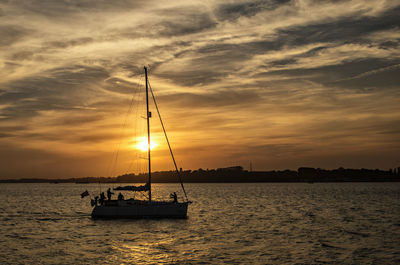 Silhouette sailboat sailing on sea against sky during sunset