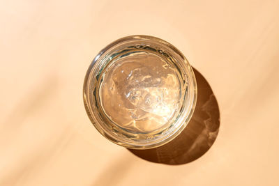 Jar with transparent cosmetic product, gel or cream on beige colored background. unbranded package 