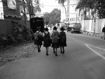 Rear view of people walking on road in city