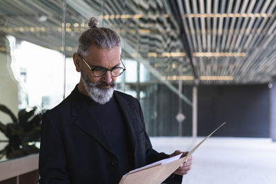 Businessman reading file in front of building