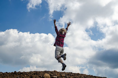 Low angle view of man jumping against sky