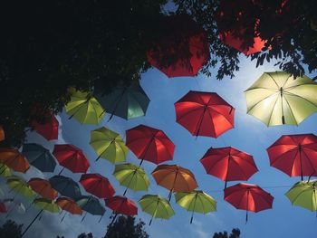 Low angle view of multi colored umbrellas against blue sky