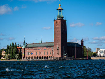 Lighthouse by sea against buildings in city