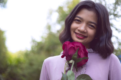 Portrait of smiling young woman against red flowering plants