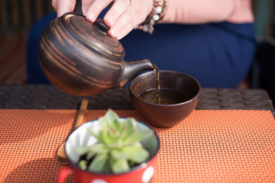 Close-up of hand pouring drink in bowl at table