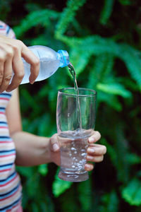 Woman holding bottle and pouring water into a drinking glass