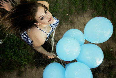 Rear view of woman holding balloons on field