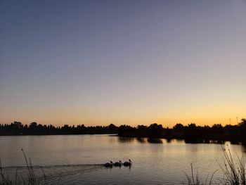 Scenic view of lake against clear sky during sunset