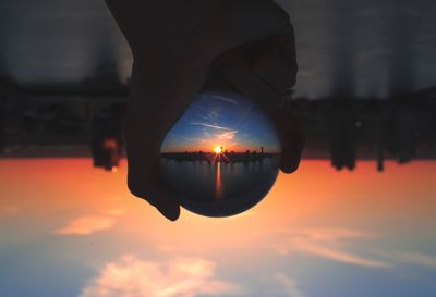 Close-up of hand against illuminated sky during sunset