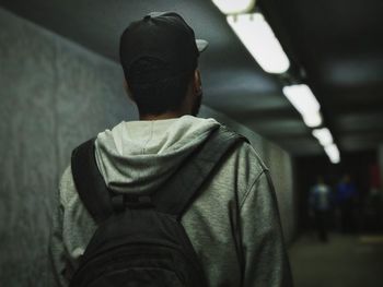 Rear view of man standing in illuminated underpass