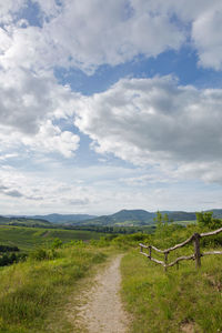 Road amidst field against sky