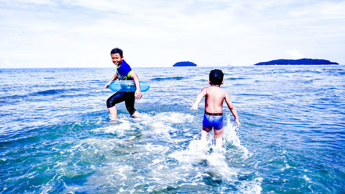 Boys playing in sea against sky