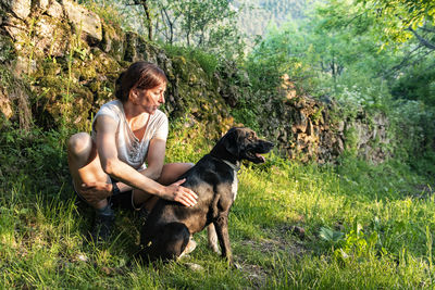 Woman petting and playing with her dog in a forest.