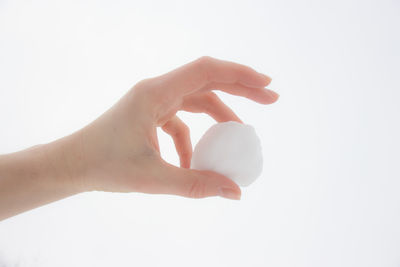 Close-up of hand holding ball against white background