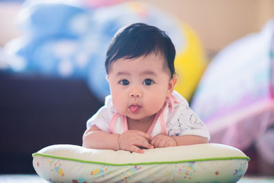 Portrait of cute baby girl lying on pillow at home