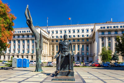 Statue in city against blue sky