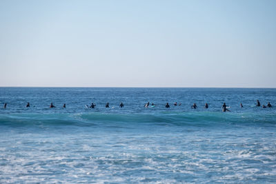 People swimming in sea against clear sky