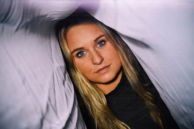 Portrait of woman under textile at home