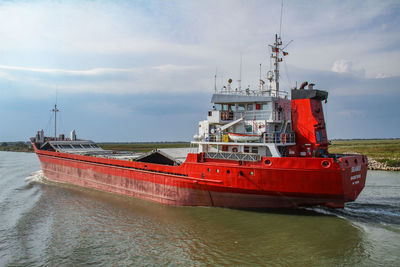 Red ship moored on sea against sky