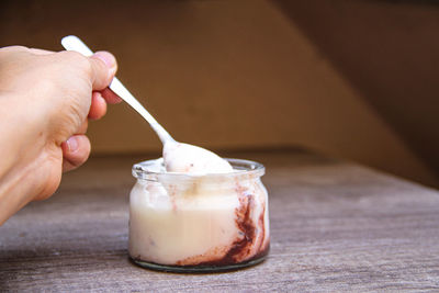 Close-up of hand holding ice cream on table