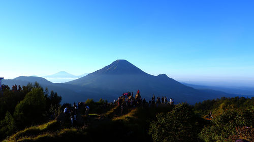 People on mountain against clear blue sky