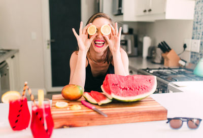 Smiling young woman with fruits on table at home