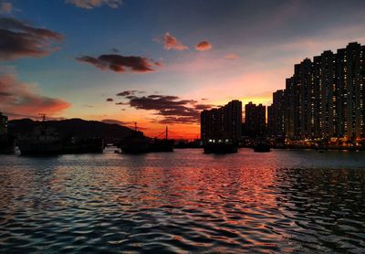 Scenic view of sea by buildings against sky during sunset