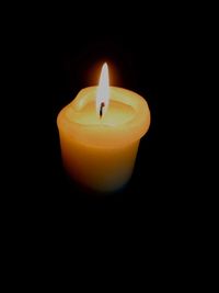 Close-up of lit candle in darkroom