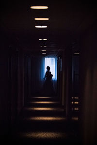 Rear view of silhouette man walking in illuminated building